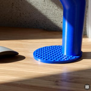 K&ouml;nnte beinhalten: Ein leuchtend blaues, zylindrisches Objekt mit einer strukturierten, kreisf&ouml;rmigen Basis. Die Basis weist kleine, gleichm&auml;&szlig;ig verteilte Noppen auf. Das Objekt steht auf einer Holzoberfl&auml;che, mit einem grauen, ovalen Objekt im Hintergrund.