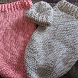 May include: Two knitted baby sleeping bags, one pink and one beige, with a matching beige knitted hat.