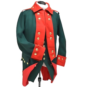 Puede incluir: Una chaqueta de estilo militar verde y roja con botones dorados. La chaqueta presenta un cuello alto y detalles rojos en las solapas, puños y paneles delanteros. La prenda se exhibe en un maniquí, mostrando su diseño.