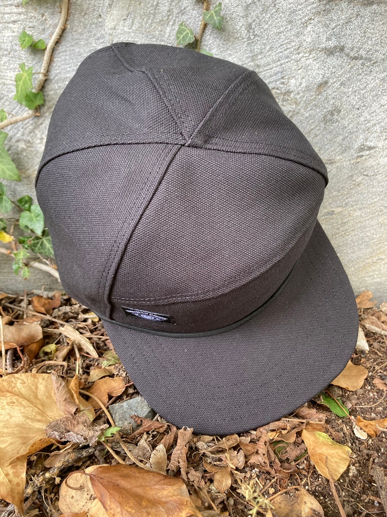 May include: A black canvas baseball cap with a flat brim and a small logo on the front.