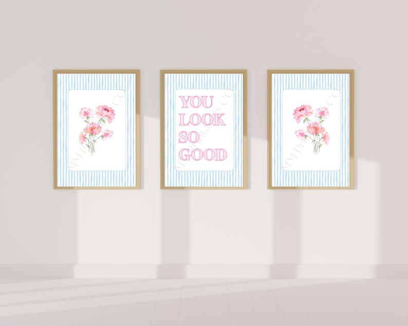 May include: Three framed art prints. Two prints feature pink floral bouquets on a white background with blue striped borders. The center print has the text "YOU LOOK SO GOOD" in pink on a white background.