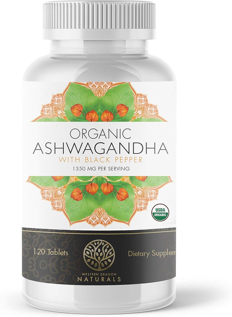 May include: A white bottle of dietary supplements labelled "Organic Ashwagandha with Black Pepper." The label features a green and orange floral design and the text "1350 MG PER SERVING." The bottle contains 120 tablets and is USDA Organic certified.
