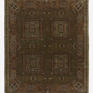 May include: A rectangular, olive green rug with a detailed geometric pattern. The rug features four central square designs with intricate borders in shades of brown and beige. The outer border has a repeating pattern.