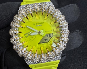 May include: A neon yellow G-Shock Casio watch with a diamond-encrusted bezel. The watch face displays the time as 9:20 and the date as 44. The watch has a neon yellow band and a black background.