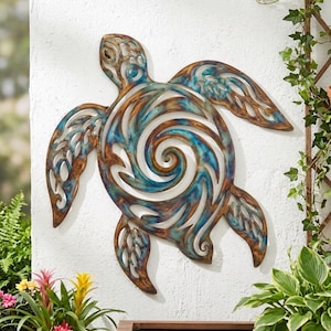 May include: A sea turtle wall sculpture crafted from metal, featuring a cut-out design with a central spiral pattern. The surface displays a weathered finish with blended tones of metallic bronze, copper, and vibrant teal blue throughout the body.