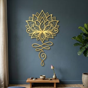 Könnte beinhalten: Goldene Lotusblumen-Wanddekoration. Das detaillierte Design zeigt eine Blume mit einem stilisierten Symbol darunter. Das Kunstwerk ist an einer dunkelblauen Wand angebracht und erzeugt einen auffälligen Kontrast. Das Stück verleiht jedem Raum einen Hauch von Eleganz und Spiritualität.