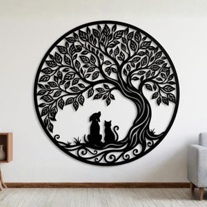 Può includere: Un'opera d'arte da parete in metallo nero raffigurante un albero della vita. Il design circolare presenta foglie e rami ritagliati con precisione, con una silhouette di cane e gatto alla base. L'opera è montata su una parete bianca.