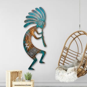 May include: Metal wall art of a Kokopelli figure, a Native American symbol. The artwork has a turquoise and copper colour scheme with geometric patterns. The figure is playing a flute, with a decorative headdress.