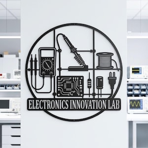 May include: A circular black metal wall sign featuring the text "ELECTRONICS INNOVATION LAB" at the bottom. The design includes silhouettes of a multimeter with probes, a soldering iron, a spool of wire, a circuit board, a resistor, a capacitor, and a plug.