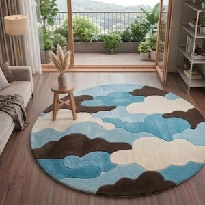 May include: A large circular area rug featuring a layered, abstract pattern of clouds in shades of light blue, medium blue, cream, and dark brown. The rug has a soft, textured appearance with distinct, curved shapes that overlap to create a sky-like design.
