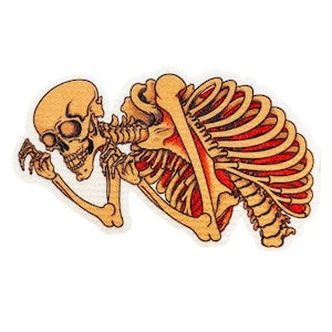 May include: An embroidered patch featuring a human skeleton in a fetal position. The bones are rendered in shades of tan and yellow, while the rib cage area is filled with vibrant red thread, creating a detailed anatomical illustration.
