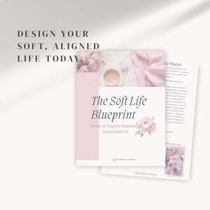 May include: A soft pink and white image featuring a book titled "The Soft Life Blueprint." The book cover has text and a floral design. The image also includes a cup of coffee and a page of text. The text reads "Design Your Soft, Aligned Life Today."