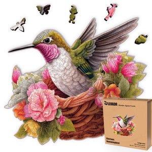 May include: A wooden jigsaw puzzle featuring a hummingbird in a nest surrounded by pink and orange flowers. The puzzle pieces are shaped to create the bird and its floral surroundings. The box shows the completed puzzle and reads "Glorious Hummingbird".