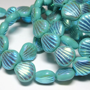 May include: A strand of turquoise blue glass beads with a shell-like design. The beads have an iridescent finish, creating a shimmering effect.