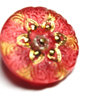 May include: A red glass button with a gold floral design and a five-pointed star in the center.