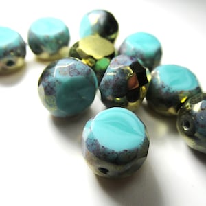 May include: A collection of turquoise and gold-colored beads. The beads have a faceted design with a mix of opaque and translucent sections. Some beads have a dark, speckled pattern.