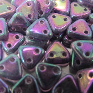 May include: A close-up of a pile of iridescent purple triangle beads with two holes each. The beads have a metallic sheen and are perfect for jewelry making.