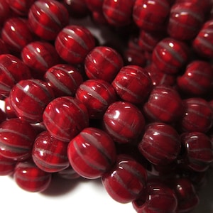 May include: A strand of red and white striped glass beads. The beads are round and have a glossy finish.