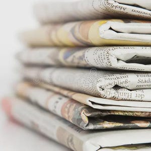 May include: A stack of folded newspapers, with visible text and varying colors. The edges of the papers are visible, showing the layered arrangement. The papers are stacked on a white surface.
