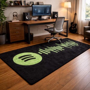 May include: Black rectangular rug featuring a green Spotify logo and soundwave pattern. The rug is positioned on a wooden floor in a home office, with a desk, computer, and speakers in the background.