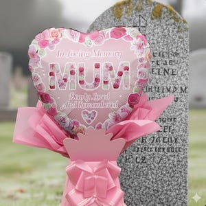 May include: A heart-shaped pink balloon with floral accents and the word "MUM" in large letters. The balloon is surrounded by pink tissue paper and a pink bow. Text on the balloon reads "In Loving Memory" and "Dearly Loved And Remembered."