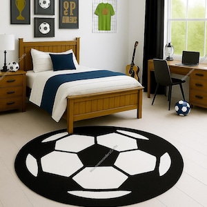 Puede incluir: Un dormitorio con temática de fútbol. La habitación cuenta con una cama de madera con un edredón a rayas azules y blancas, una alfombra con forma de balón de fútbol y obras de arte enmarcadas con temática de fútbol. Una camiseta verde cuelga de la pared. Un balón de fútbol está en el suelo.