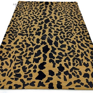 May include: A rectangular area rug with a leopard print design. The rug features a tan background with irregular black spots. The rug is made of a woven material and is suitable for a living room or bedroom.