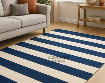 May include: A rectangular rug with alternating wide navy blue and off-white stripes. The rug is placed on a hardwood floor in a living room setting. The text "A.G.RUGS STUDIO" is visible on the rug.