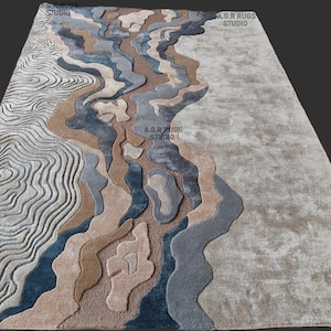 Può includere: Un tappeto rettangolare con un design paesaggistico. Il tappeto presenta un motivo di forme fluide nelle tonalità del beige, marrone, blu e grigio. Il tappeto ha un aspetto strutturato e le parole "A.D.R RUGS STUDIO" sono visibili.