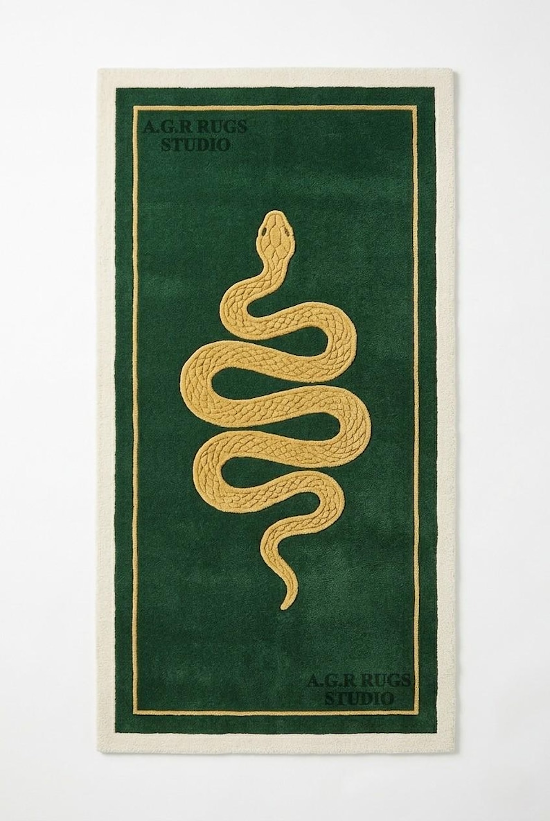 May include: A rectangular rug featuring a deep green field with a central golden yellow snake motif. The rug has a cream-colored border and a thin golden yellow inner frame. The text A.G.R RUGS STUDIO is printed in the top left and bottom right corners.