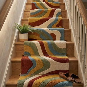 May include: A staircase runner featuring a wavy, multi-colored pattern in shades of rust, mustard yellow, sage green, and cream. The runner is secured with brass rods on each step. A small potted fern and a pair of brown leather slippers are present.