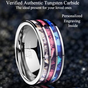 May include: A silver tungsten carbide ring with a patterned inlay in shades of pink, blue, and white. The ring features the text "Tungsten Carbide". The image also includes the text "Verified Authentic Tungsten Carbide" and "Personalized Engraving Inside."