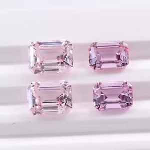 May include: Four light pink emerald-cut gemstones. Each gem has a rectangular shape with cut facets, reflecting light. The stones are displayed on a white surface, showcasing their clarity and colour.