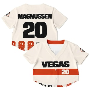 Op de afbeelding: Cr&egrave;mekleurig honkbalshirt met de zwarte tekst "MAGNUSSEN 20" op de rug en "VEGAS 20" op de voorkant. De voorkant heeft een rode streep. Een klein logo staat op de mouw.