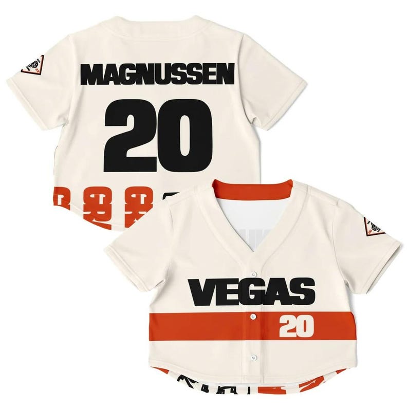Op de afbeelding: Cr&egrave;mekleurig honkbalshirt met de zwarte tekst "MAGNUSSEN 20" op de rug en "VEGAS 20" op de voorkant. De voorkant heeft een rode streep. Een klein logo staat op de mouw.