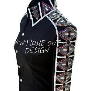 Könnte beinhalten: Schwarzes Hemd mit Knöpfen und dekorativen Verzierungen. Kragen und Schultern weisen geometrische Muster mit farbigen Strasssteinen und silbernen Akzenten auf. Der Text "ANTIQUE ONE DESIGN" ist auf dem Hemd geschrieben.