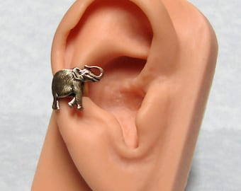 May include: A gold-toned elephant ear cuff earring. The earring is shown on a model ear.