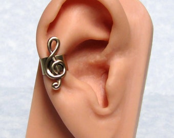 May include: A gold-tone treble clef ear cuff. The cuff is designed to sit on the upper part of the ear, just above the cartilage.
