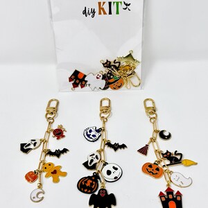 May include: Halloween-themed keychain DIY kit with gold-colored chains and charms. Charms include ghosts, bats, pumpkins, and a haunted house. The kit's packaging reads "KEYCHAIN diy KIT" in colorful letters.