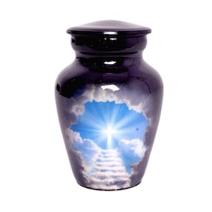 Puede incluir: Una urna de cremación de color morado oscuro con acabado brillante y un estampado central que muestra un sol brillante entre nubes con una escalera que conduce hacia una luz resplandeciente, rematada con una tapa extraíble a juego.