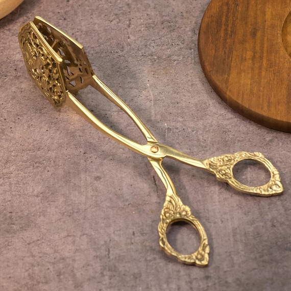 Heavy antique-finish brass tongs that look like they belong in a 19th-century apothecary kitchen — a genuinely rare handcrafted Indian brass utensil with real collectible appeal.