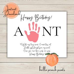 May include: A white printable card with the words "Happy Birthday!" and "AUNT" in black. A pink handprint is in the center. The card includes a peach illustration and the text "With my tiny hand..." and "hello peach prints."