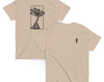 May include: Two beige t-shirts. One features a black illustration of a tree and a figure within a rectangular frame, with the text "NAMIBIA ROADSIDE" above. The other shirt has a small black graphic on the chest.