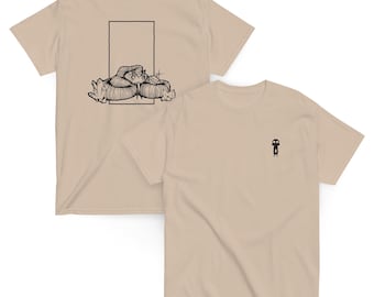 May include: Two beige t-shirts. One displays a black graphic of a person with a hat on the front. The other shirt has a black illustration of a person with a hat and the text "NAMIBIA ROADRIDE" on the back.