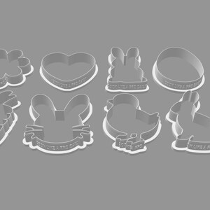 May include: A collection of eight white plastic cookie cutters in various Easter-themed shapes, including a flower, heart, bunny, egg, carrot, bunny face, chick, and rabbit. Each cutter has the text "COOK LIKE A PRO DAILY".