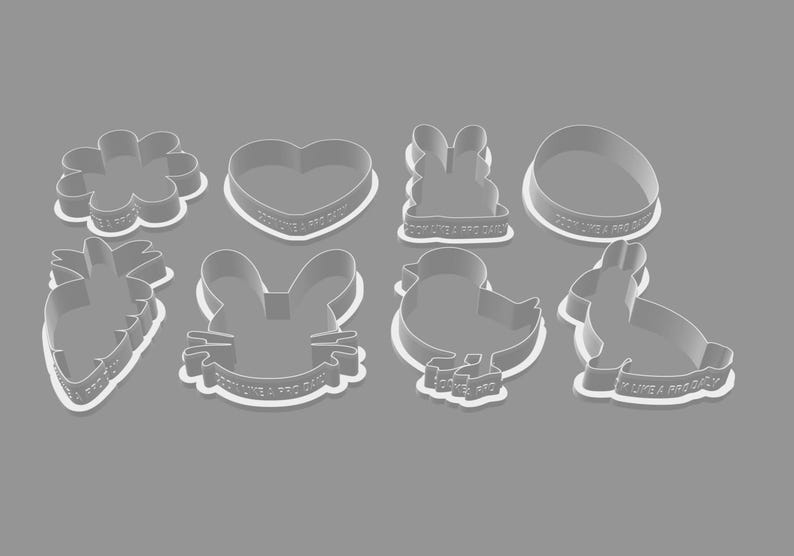 May include: A collection of eight white plastic cookie cutters in various Easter-themed shapes, including a flower, heart, bunny, egg, carrot, bunny face, chick, and rabbit. Each cutter has the text "COOK LIKE A PRO DAILY".