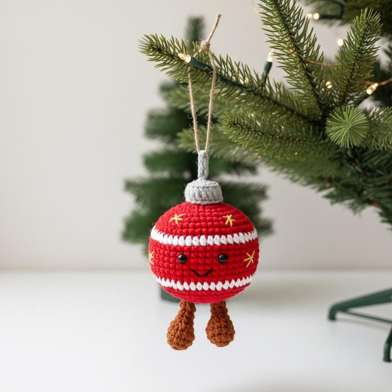 Peut inclure: Une d&eacute;coration de No&euml;l crochet&eacute;e rouge et blanche avec un visage souriant et des jambes marron. L'ornement est d&eacute;cor&eacute; d'&eacute;toiles jaunes et de rayures blanches. Il est suspendu &agrave; une ficelle sur un sapin de No&euml;l.