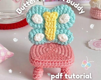 May include: A handmade crochet butterfly stool buddy in pastel colors. The butterfly is light blue with yellow and white accents, perched atop a pink stool. The text "Butterfly stool buddy" and "pdf tutorial" are visible.