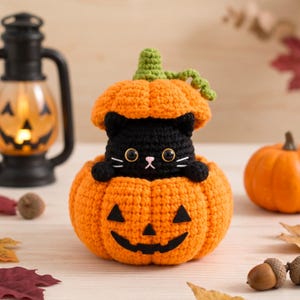 May include: A crocheted black cat figurine peeking out from inside a bright orange pumpkin with a jack-o'-lantern face. The pumpkin has a green stem on top and black felt eyes and a mouth. The cat has large black eyes and white whiskers.
