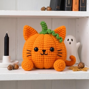 Peut inclure: Une citrouille orange crochetée en forme de chat avec une tige verte, des yeux en plastique noir et des moustaches brodées. La figurine en peluche présente deux oreilles pointues, deux pattes avant rondes et une queue recourbée.